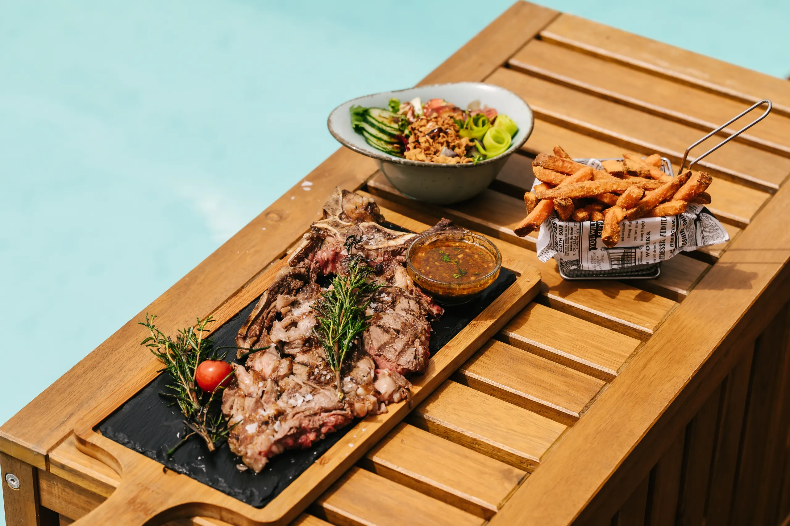 Ribeye with salad and fries by the pool in Marbella