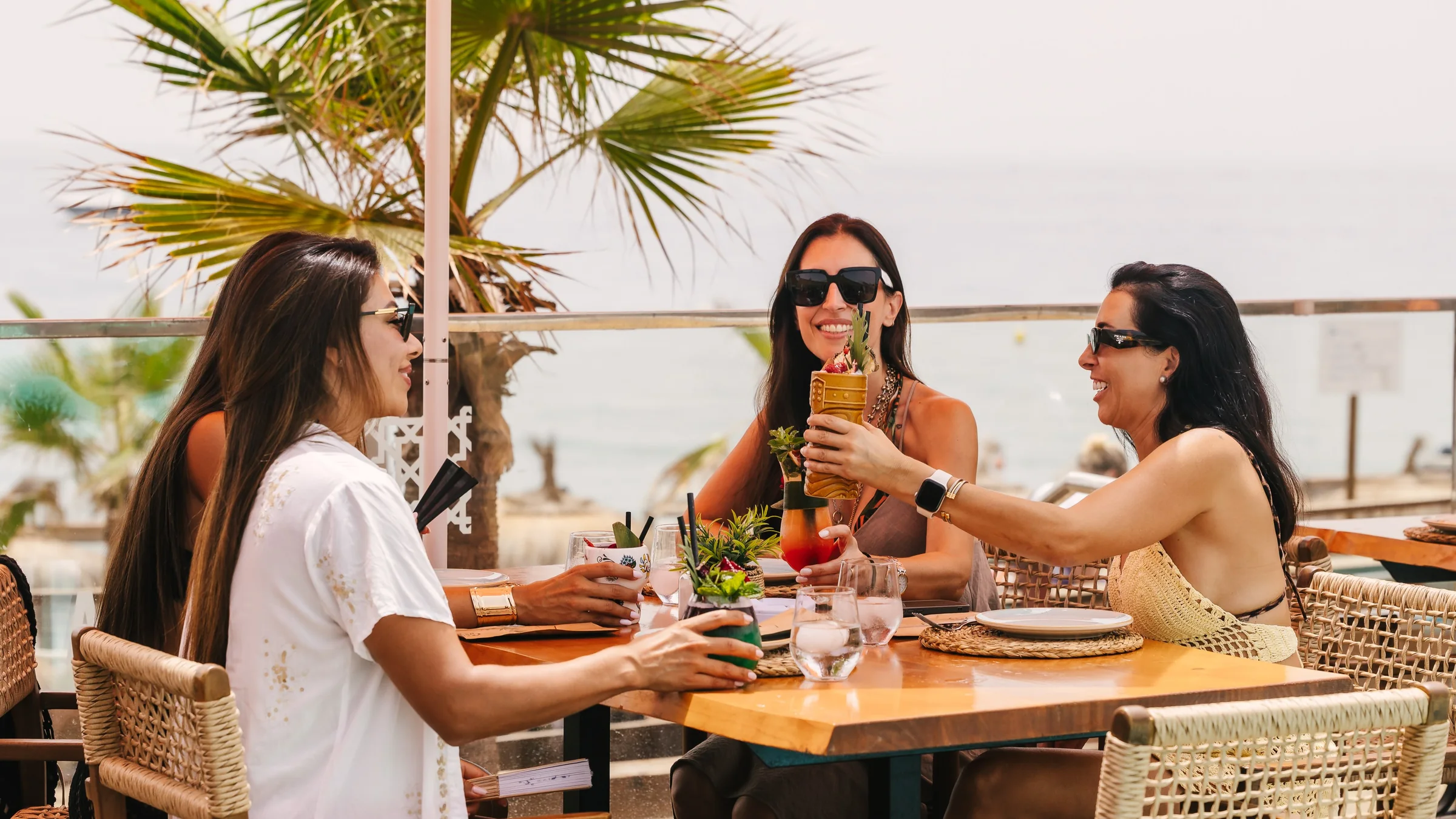 Amigas brindando con cócteles en la zona chill-out y lounge frente al mar de The Point Marbella