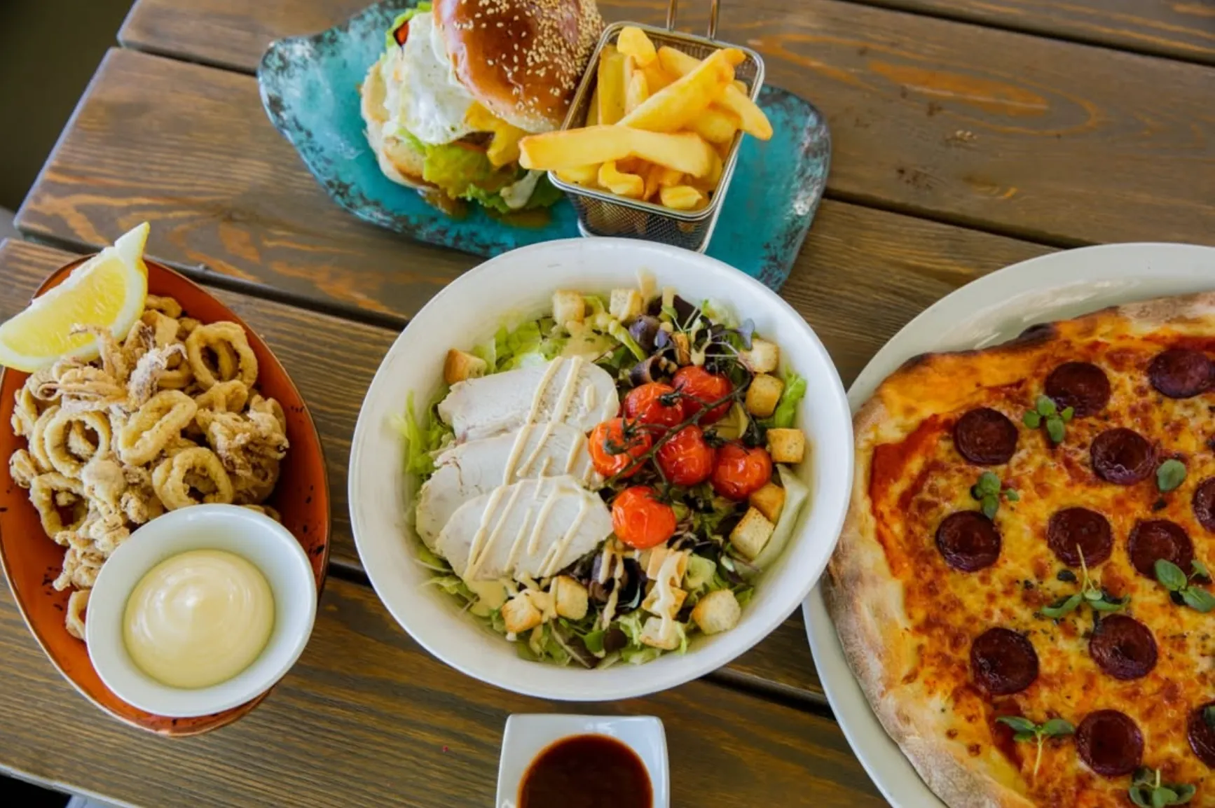 Table with pizza, salad, calamari and a burger at The Point, a beachside restaurant in Marbella