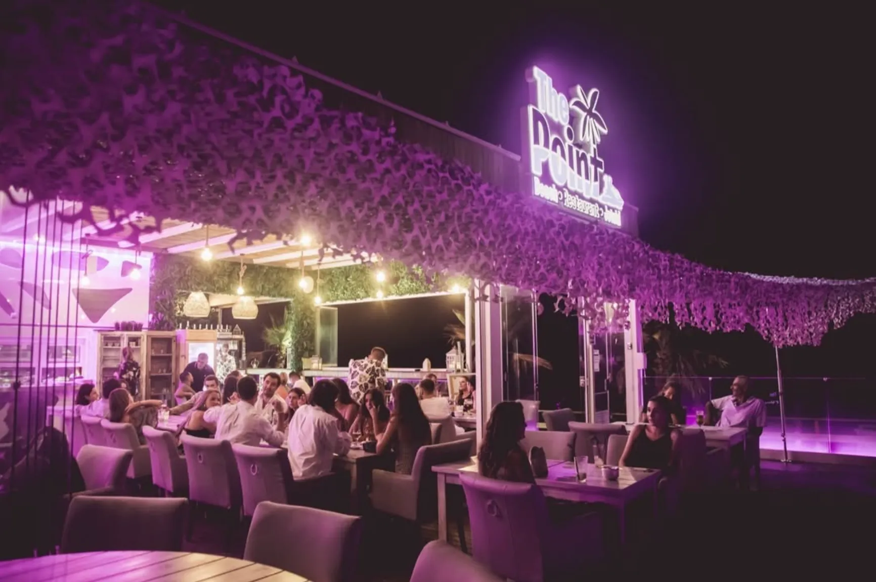 Terraza del restaurante de noche con el letrero de neón de The Point Marbella